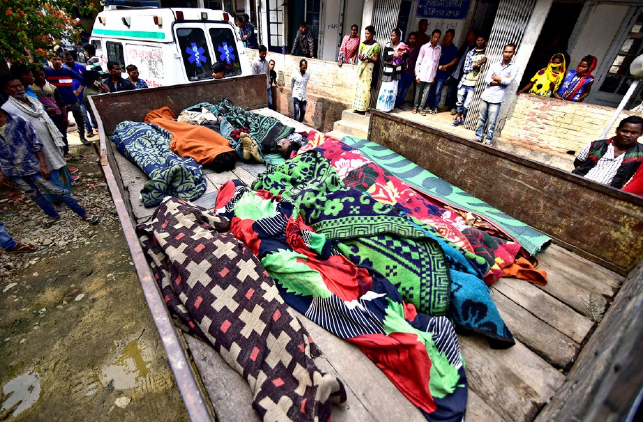 ORANG ramai melihat mayat pekerja ladang teh yang maut akibat keracunan arak. FOTO Reuters