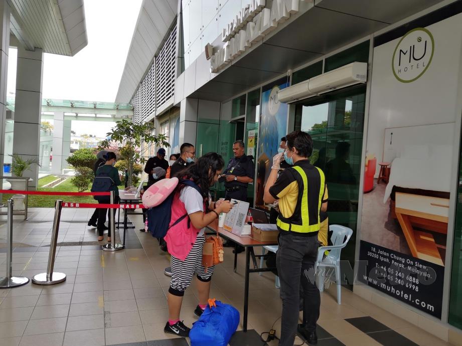 PENUMPANG yang mahu berlepas ke Singapura mendaftar masuk dan diperiksa suhu sebelum dibenarkan masuk ke ruang menunggu di dalam Lapangan Terbang Sultan Azlan Shah (LTSAS). FOTO BALQIS JAZIMAH ZAHARI