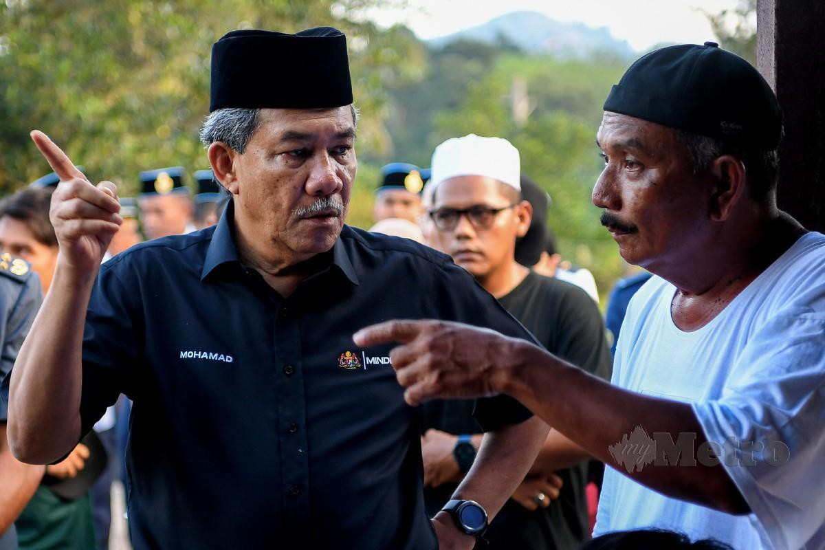 MOHAMAD menyantuni Masdi, bapa kepada arwah Mohd Iqmal pada majlis pengebumian di Tanah Perkuburan Kampung Rawa Hulu, Lenggeng. FOTO Bernama 