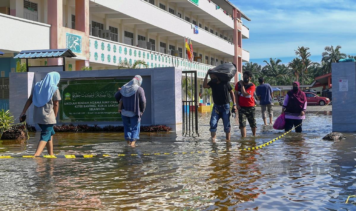 Mangsa banjir meredah takungan air banjir di pintu masuk pusat penempatan sementara (PPS) Sekolah Rendah Agama Bukit Changgang hari ini. FOTO BERNAMA