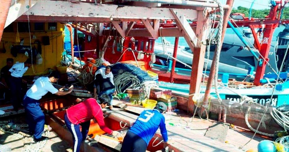 ANGGOTA APMM memeriksa bot nelayan asing yang ditahan di Jeti APMM Kemaman di Chukai, semalam. FOTO Rosli Ilham.