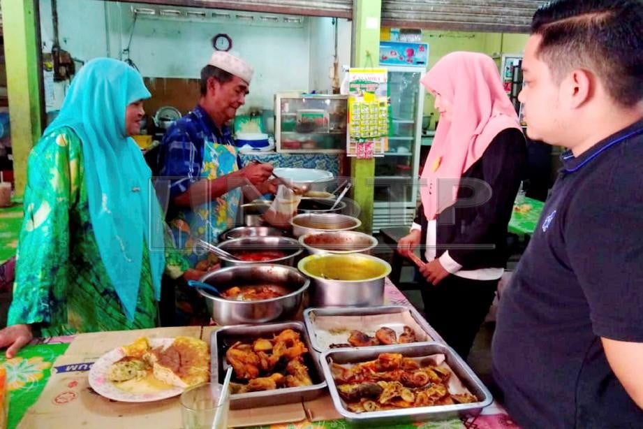 MAT Zain Hamat, 71, (dua kiri, berkopiah) dan dibantu isterinya, Hasnah Idris, 69 (kiri) melayan pelanggan yang datang membeli nasi di kedainya di Pasar Melor. FOTO Hazira Ahmad Zaidi