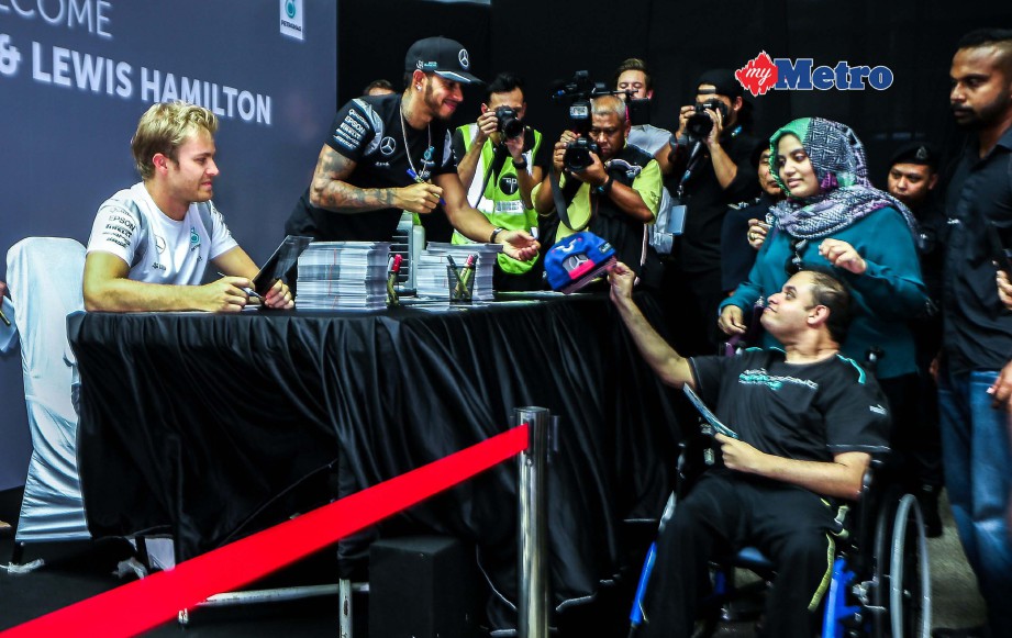 Peminat F1, Hafiz Mohamed Siraj, 29, (kanan) tidak melepaskan peluang bertemu Rosberg dan Lewis Hamilton. FOTO NSTP/OSMAN ADNAN 