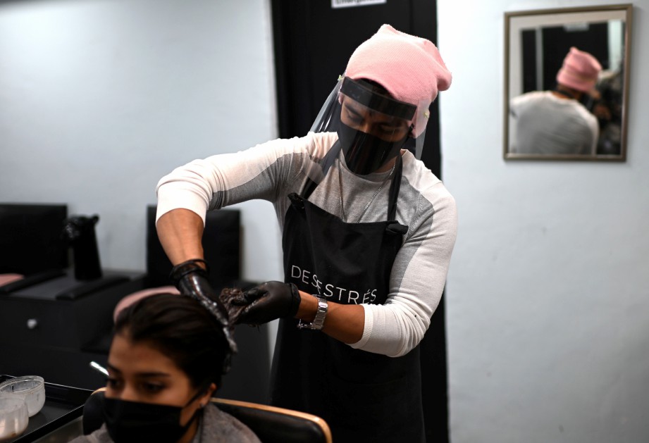 PEKERJA salun mengamalkan langkah pencegahan ketika mewarnakan rambut pelanggan di Mexico City. FOTO AFP 