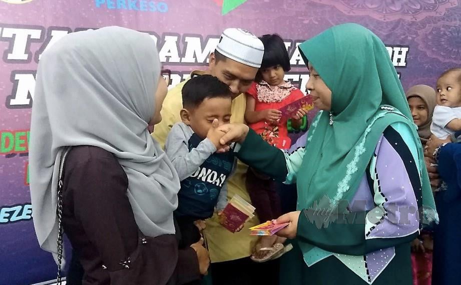 MOHAMAD Khairul Haziq Abdul Hadi, 5, mencium tangan Pengarah PERKESO Terengganu, Farihah Che Husin (tengah) selepas menerima duit raya pada Majlis Iftar Ramadhan di Wisma PERKESO. FOTO Zaid Salim