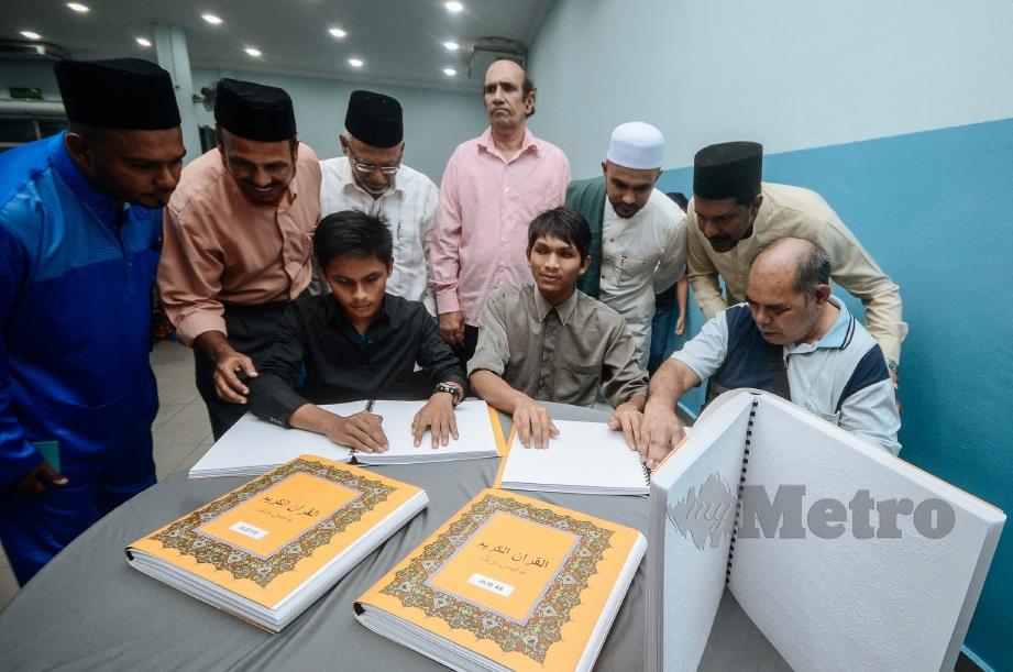 MOHAMED Aswan (berdiri dua dari kanan) beramah mesra dengan penerima al-Quran Braille iaitu Muhammad Sirajuddin (duduk tengah), Ramli Abdul Rahman, 58 (duduk kanan) dan Muhammad Danish Isyraq Ab Ghani, 16 (duduk kiri) di Georgetown. FOTO Shahnaz Fazlie Shahrizal.