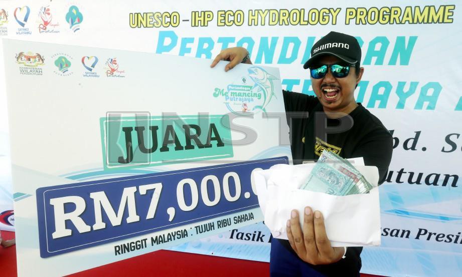 Mohd Hazari Ramlan bergambar bersama wang tunai selepas menjadi Juara pertandingan Pertandingan Memancing Putrajaya sempena Hari Wilayah Persekutuan di Putrajaya. FOTO Mohd Fadli Hamzah
