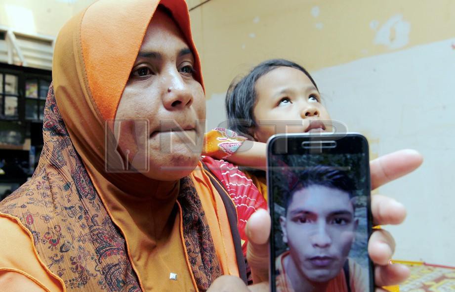 ROHANI bersama ahli keluarga menunjukkan gambar Mohd Asri. FOTO Syamsi Suhaimi