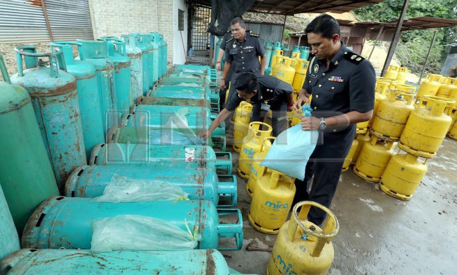 Mohd Suffian (kanan) memeriksa sebahagian 225 gas petroleum cecair (LPG) bersubsidi di sebuah stor haram di Kampung Teluk Sungai Kecil, Nibong Tebal. FOTO Rosli Ahmad.
