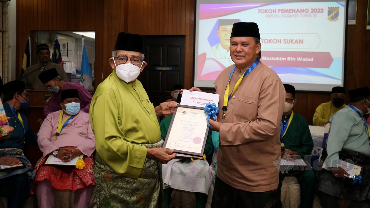 PRESIDEN Persatuan Melayu Pulau Pinang (Pemenang), Tan Sri Mohd Yussof Latiff, menyampaikan pingat dan sijil perhargaan Tokoh Sukan kepada Mustakim Walad. FOTO Mikail Ong