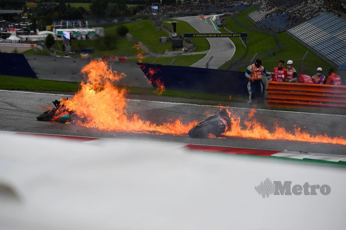 MOTOSIKAL milik Savadori dan Pedrosa terbakar selepas kemalangan di pusingan awal GP Styria di Litar Red Bull Ring di Spielberg, hari ini. FOTO AFP