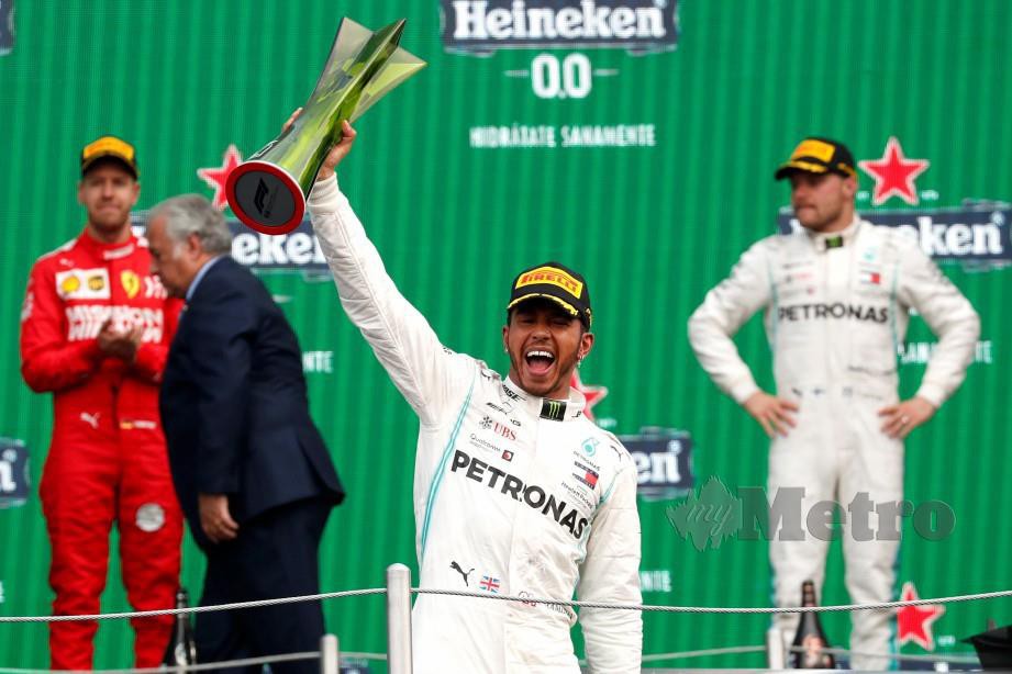 Hamilton (tengah) meraikan kejayaan bersama trofi dimenangi pada GP Mexico. FOTO Reuters
