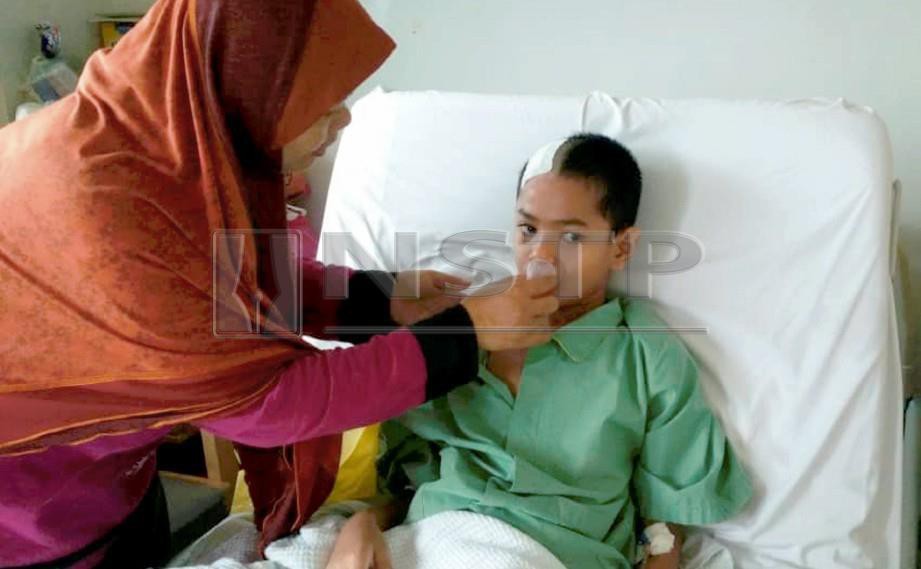 CHE Anisah Md Saad,42, memberikan ubat cecair kepada anaknya Muhammad Azwar Mohd Ariff, 11, yang masih tidak bermaya selepas menjalani pembedahan di bahagian kepala di Hospital Sultanah Bahiyah (HSB). FOTO Noorazura Abdul Rahman