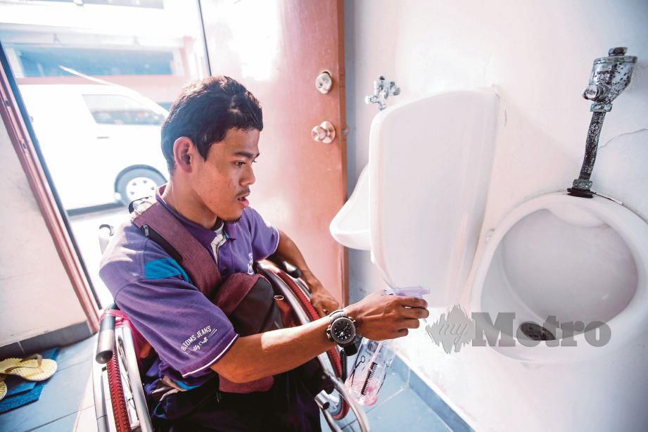 Muhammad Helmi Firdaus atau Amy membersihkan tandas awam tempat dia bertugas di Puchong Perdana. FOTO Syarafiq Abd Samad.