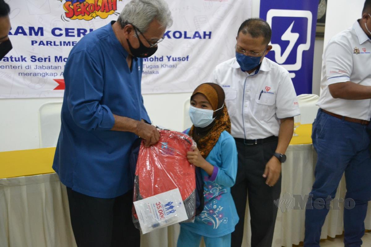 Mohd Redzuan menyampaikan peralatan persekolahan sumbangan TNB kepada murid pada program Ceria ke Sekolah Tenaga Nasional Bhd (TNB) di Dewan Anggerik, Melekek Alor Gajah. FOTO Hassan Omar