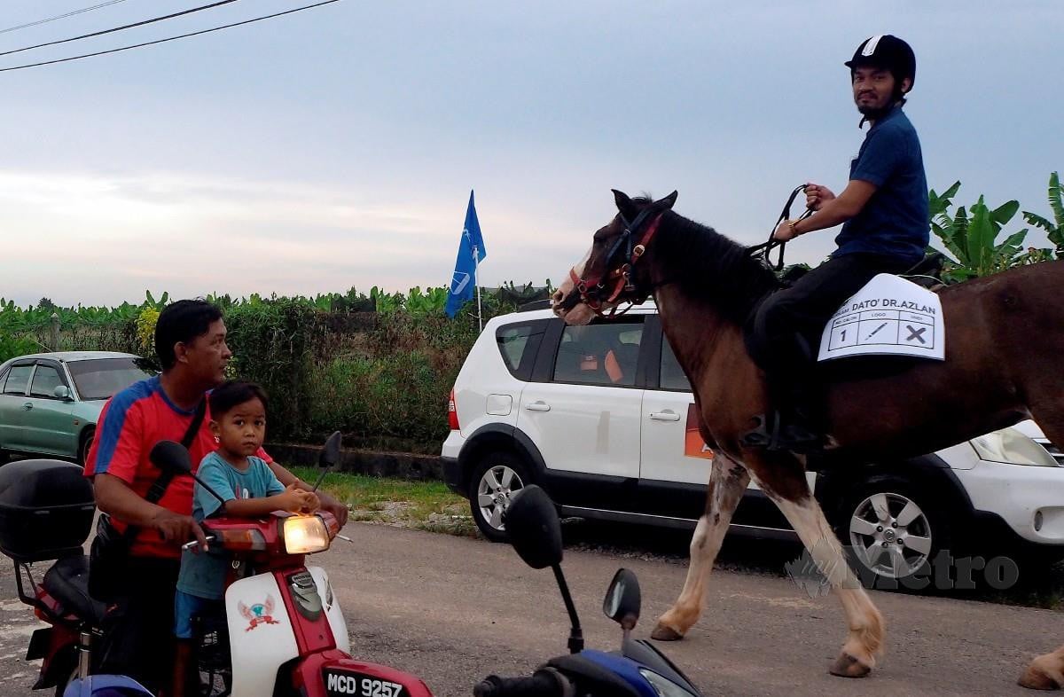 NORAZLANSHAH menunggang kuda untuk bersiar-siar di sekitar kampung  sambil berkempen. Foto Bernama