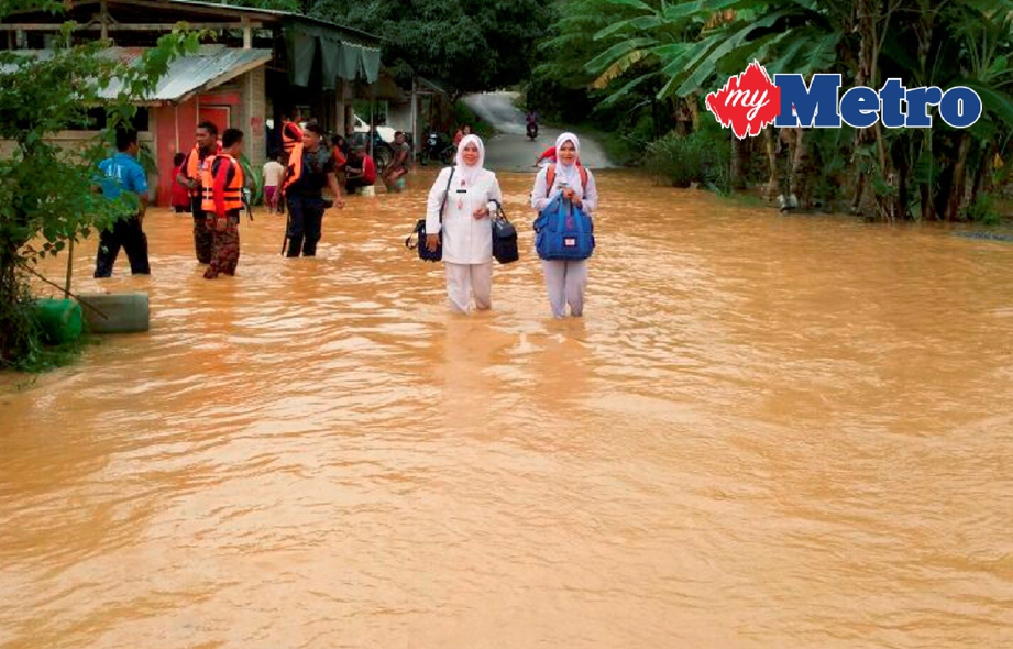 Jururawat, Normizana Zakaria ,39, (kiri) dan Norizan Junoh, 43,  mengharungi banjir baru-baru ini untuk memberi khidmat rawatan kepada penduduk. FOTO Ramli Ibrahim