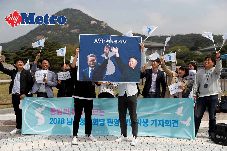 PELAJAR memegang poster dengan gambar Jae-in dan Jong Un ketika perhimpunan pro-penyatuan menjelang pertemuan antara Korea Selatan dan Korea Utara di Seoul. -Foto Reuters