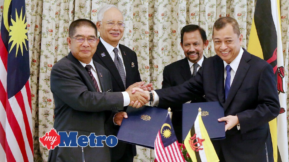 NAJIB dan Sultan Hassanal Bolkiah menyaksikan Maximus (kiri) dan Pehin Datu Mohammad Yasmin bertukar dokumen perjanjian kerjasama. FOTO Mohd Fadli Hamzah