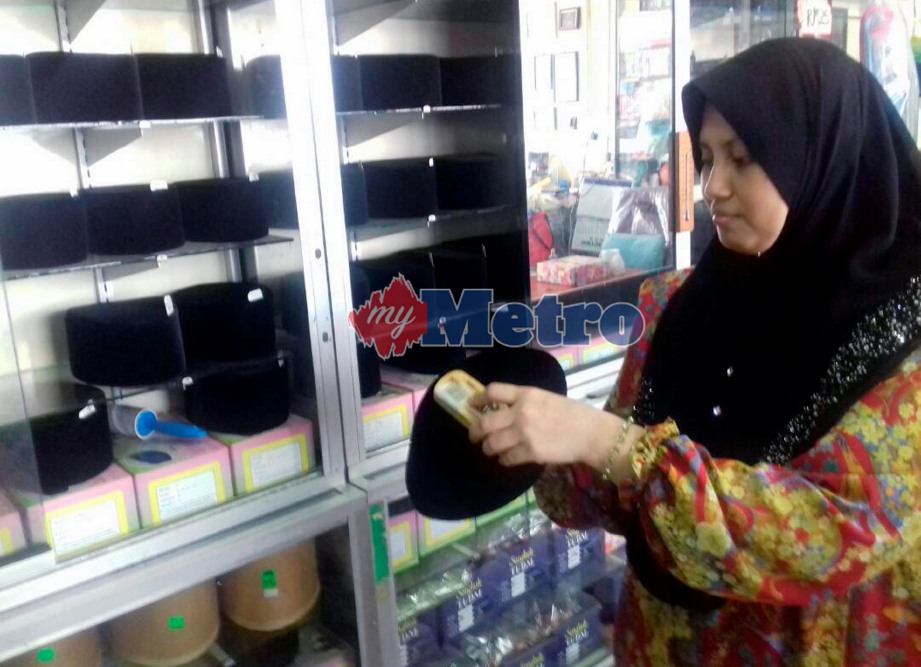 NURHAYATI Abu Bakar menunjukkan sebahagian songkok yang dijual dengan harga serendah RM24 sehingga RM190 bergantung kepada saiz dan kualiti kain yang digunakan ketika ditemui di kedai songkok miliknya di Jalan Temenggong. FOTO Syaherah Mustafa