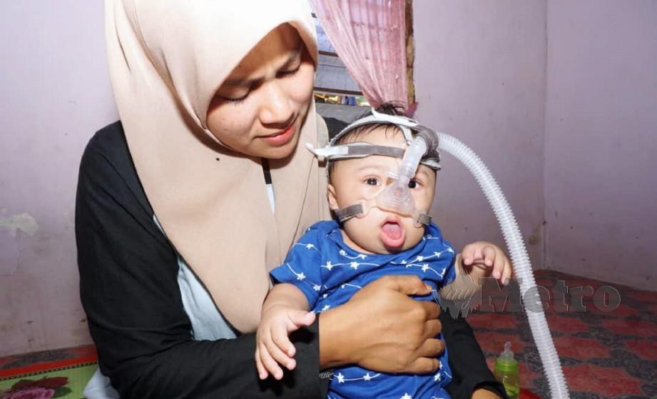 NURUL Hana Zakaria, 26, memangku anaknya Muhammad Nazmi Ammar, 10 bulan yang mempunyai masalah paru-paru sempit dan perlu menggunakan mesin oksigen bagi membantu dia bernafas. FOTO Noorazura Abdul Rahman