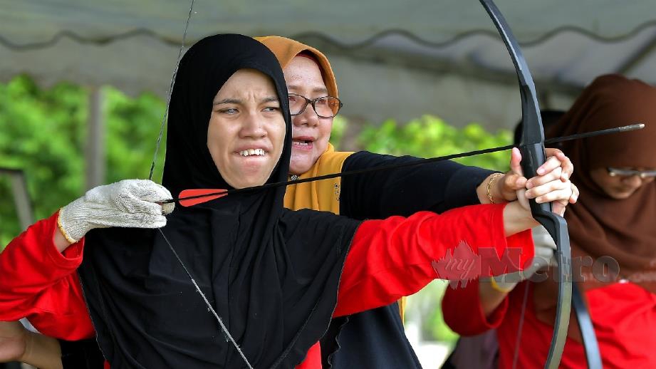 SALAH seorang peserta OKU penglihatan dibantu sukarelawan mengambil bahagian dalam acara memanah anjuran JPWKMT sempena Fit Malaysia 2019 di Batu Burok, Kuala Terengganu. FOTO BERNAMA