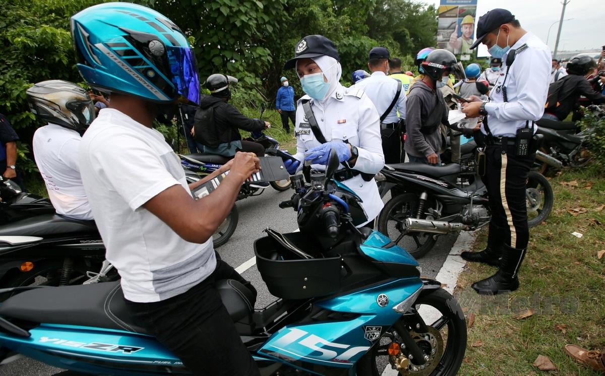 ANGGOTA polis trafik memeriksa motosikal pada operasi hari ini. FOTO EIZAIRI SHAMSUDIN