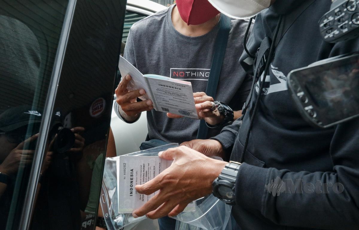 Pegawai Jabatan Pengangkutan Jalanraya (JPJ) memeriksa dokumen seorang pemandu e-hailing yang berasal dari Indonesia yang menawarkan perkhidmatan kenderaan awam secara tidak sah di Setapak Sentral. FOTO SADIQ SANI