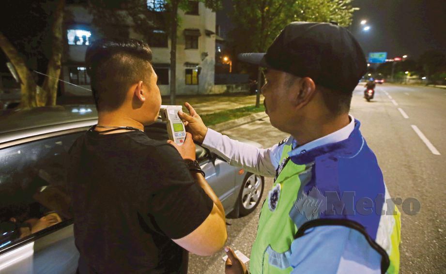 ANGGOTA Jabatan Penguatkuasaan dan Siasatan Trafik (JSPT) Kuala Lumpur memeriksa kandungan alkohol dalam kalangan pemandu. FOTO MOHD KHAIRUL HELMY MOHD DIN