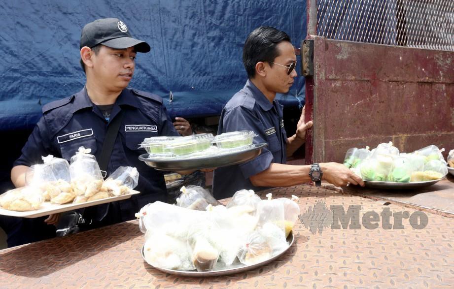 ANGGOTA penguatkuasa Majlis Perbandaran Kota Bharu-Bandar Raya Islam (MPKB-BRI) merampas makanan yang dijual di sebuah premis di Jalan Masjid Lundang, Telipot, Kota Bharu yang berniaga sebelum jam 3 petang. - FOTO Zaman Huri Isa
