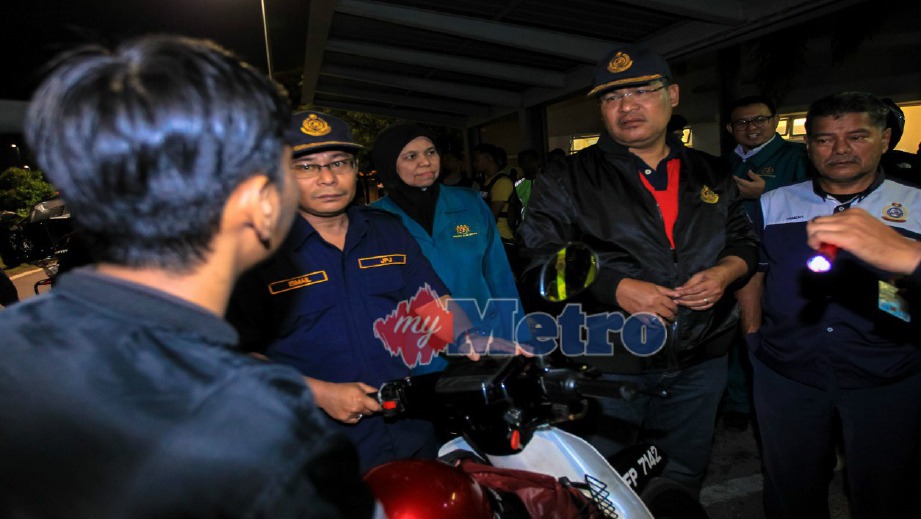 WAN Ahmad Uzir (dua dari kanan) berkata sesuatu kepada penunggang motosikal dalam operasi di Plaza Tol Batu, Lebuhraya Duke, malam tadi. FOTO Asyraf Hamzah