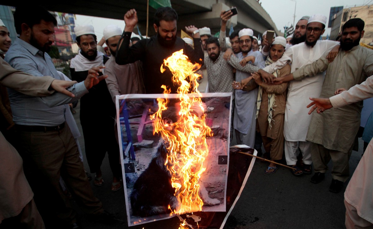 ORANG ramai membakar gambar Presiden Perancis Emmaneul Macron pada tunjuk perasaan berhampiran konsulat Perancis di Lahore, Pakistan. FOTO EPA 