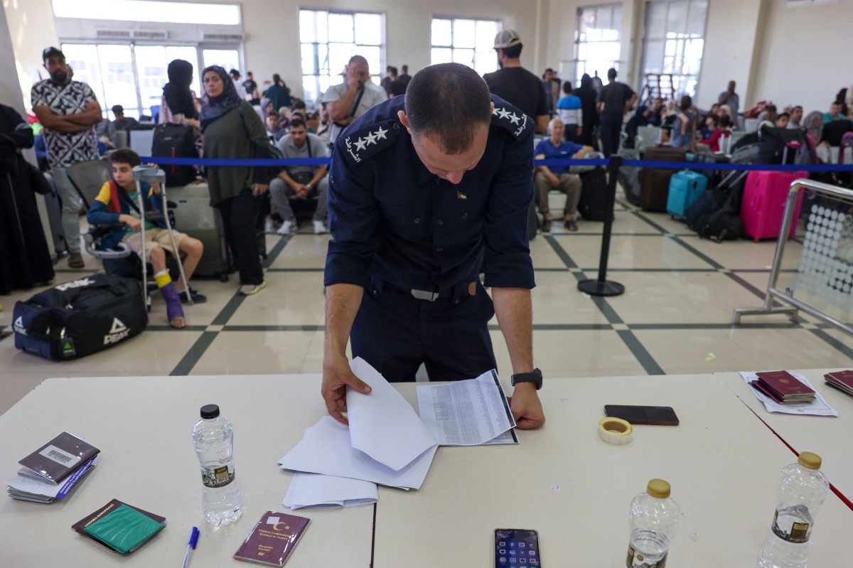 PASUKAN keselamatan memeriksa dokumen dan pemegang pasport dua kerakyatan dan warga asing di sempadan Rafah-Mesir, pada Selasa. FOTO AFP