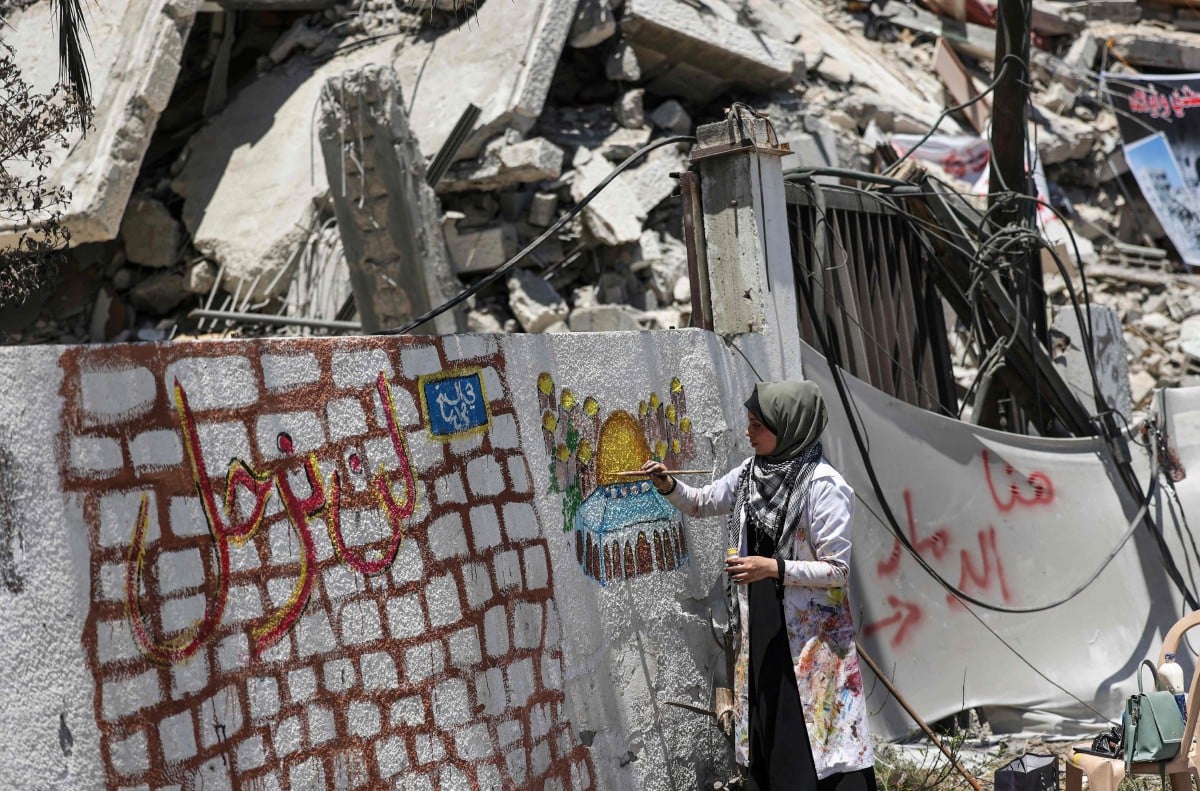 SENIMAN Palestin, Etaf al-Najili melukis Kubah Sakhrah di runtuhan bangunan di Semenanjung Gaza. FOTO AFP 