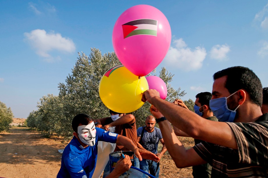 PENDUDUK Palestin yang memakai topeng dan pelitup muka menerbangkan ‘belon berapi’ dari Gaza ke kawasan dikuasai Israel. FOTO AFP 