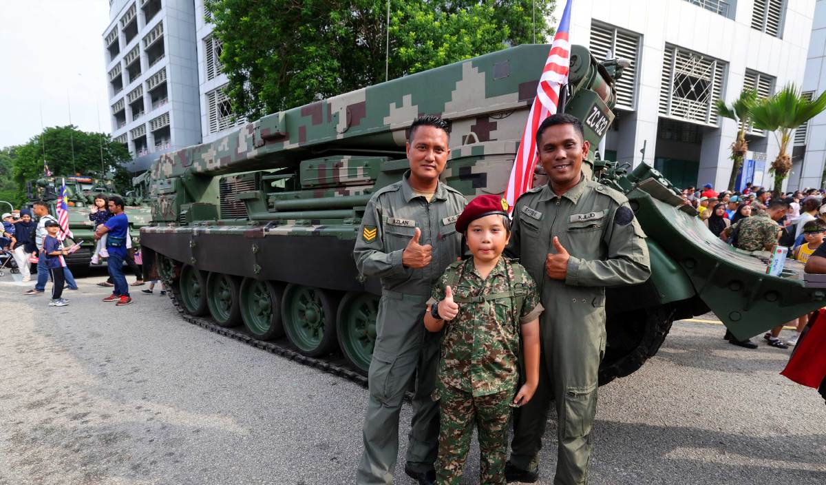 PENGUNJUNG cilik Azri Nur Iman Hayqal lengkap berpakaian tentera bergambar kenangan bersama aset Angkatan Tentera Malaysia pada sambutan Hari Kebangsaan ke-66 di Dataran Putrajaya. FOTO BERNAMA