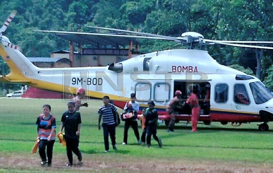 SEBAHAGIAN daripada pelajar Orang Asli yang terkandas akibat jalan rosak teruk dibawa menggunakan dua helikopter Unit Udara JBPM untuk dihantar ke sekolah menengah di sekitar Gua Musang, bermula hari ini. FOTO Ramli Ibrahim.