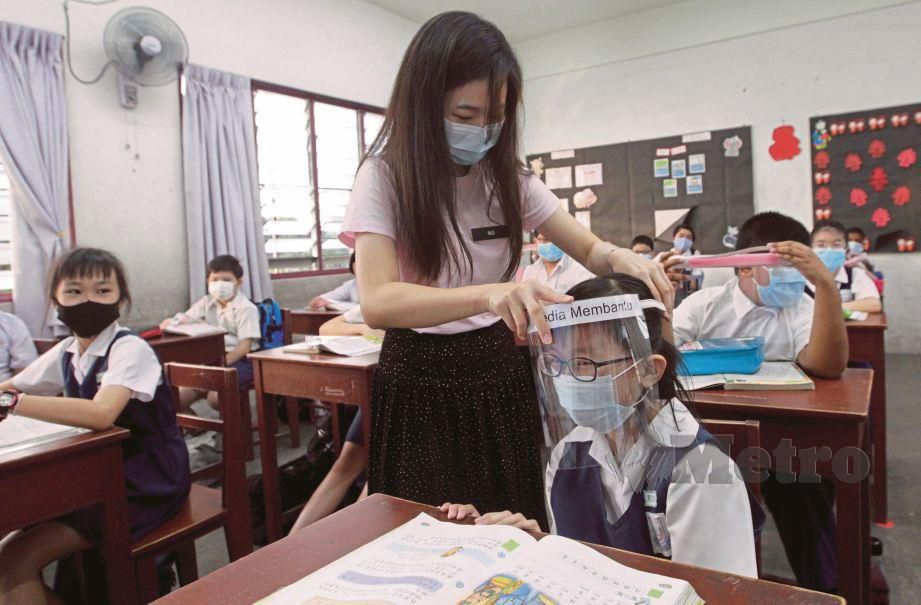  Guru membantu murid memakai pelindung muka ketika tinjauan pembukaan semula sekolah rendah di Sekolah Jenis Kebangsaan Cina (SJKC) Jelutong di sini. FOTO DANIAL SAAD 