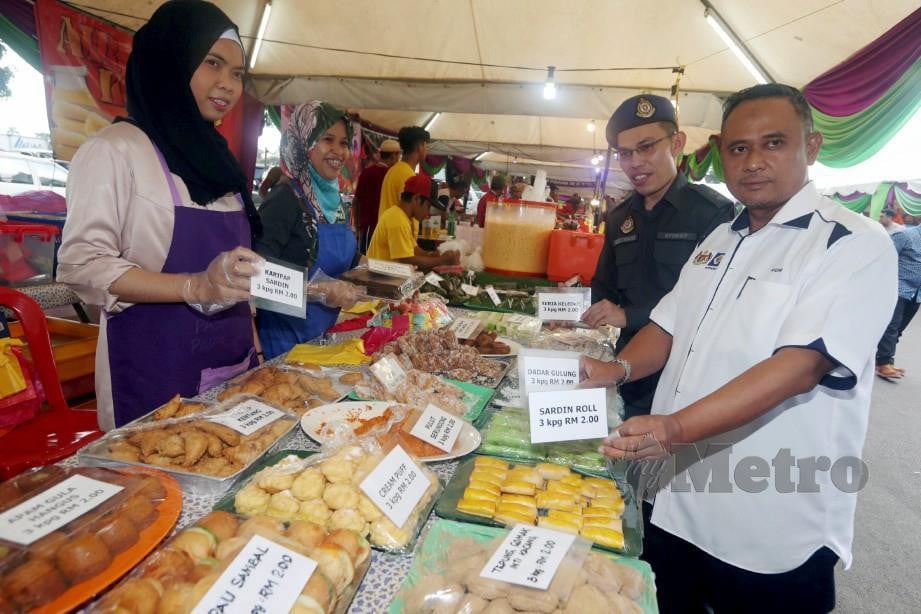 MOHD Hairul (kanan) menunjukkan contoh peniaga mempamerkan tanda harga makanan di gerai ketika pemeriksaan di Bazar Ramadan Angsana Mall, Johor Bahru. FOTO Hairul Anuar Rahim