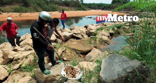 Penduduk kampung melihat tulang babi di tebing Sungai Golok berhampiran Kampung Kubang Rambutan, Rantau Panjang, dua hari lalu - Foto Fail.