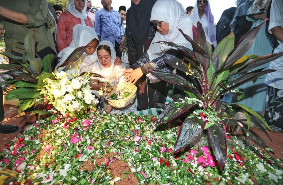 ISTERI Allahyarham Arie, Wan Edna Marina Wan Malek (dua kiri) menabur bunga di pusara suaminya di Tanah Perkuburan Islam Bukit Kiara.  - FOTO Aswadi Alias
