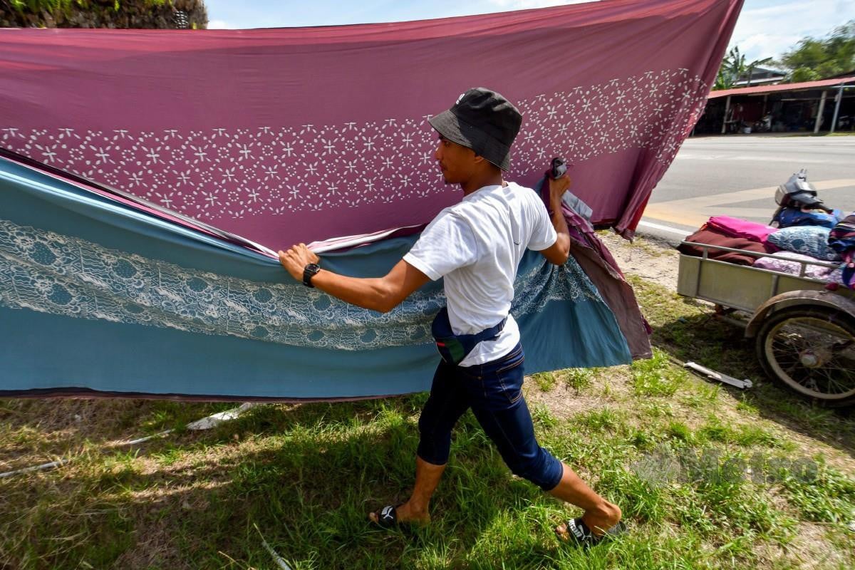 Pekerja batik Muhd Hilmi Abdullah, 29, mengangkat kain batik yang sudah dikeringkan. FOTO Bernama 