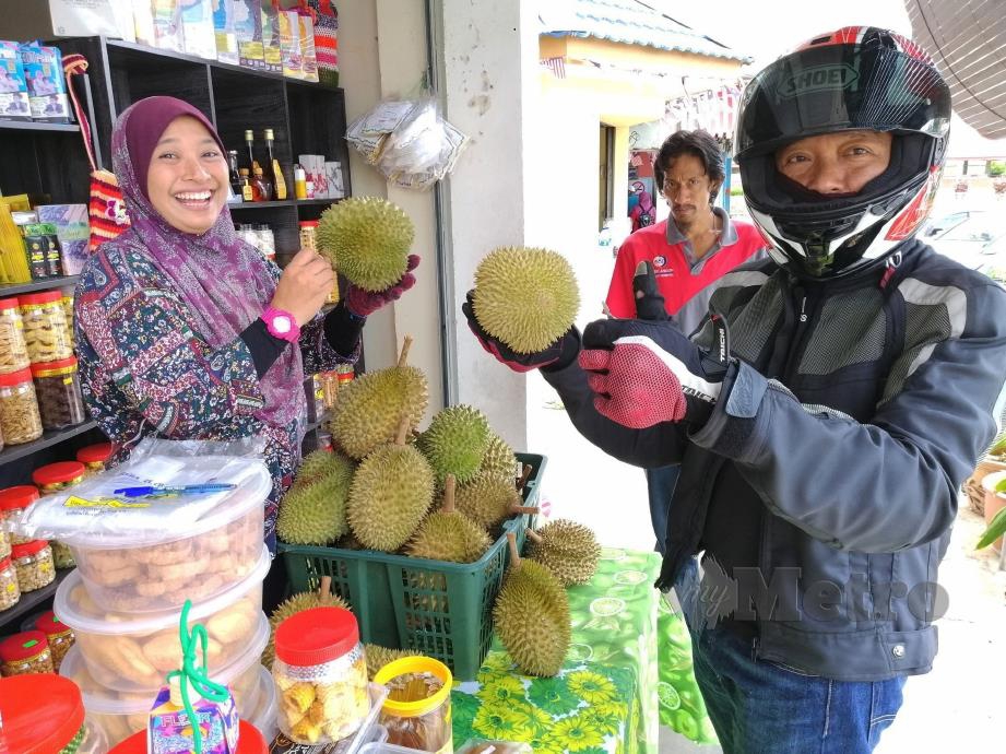 SHARIFAH Rohaizah menunjukkan durian yang dijual di gerainya di Kuala Klawang. 
