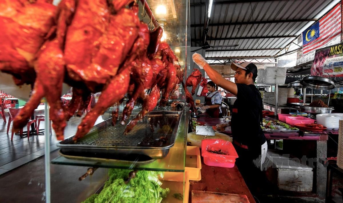 Peniaga nasi ayam Yusri Mazlan menggantung ayam yang siap masak untuk dijual kepada pelanggan ketika tinjauan di gerainya di Taman Ampangan, hari ini. FOTO BERNAMA