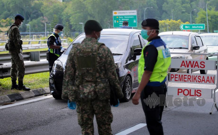 Anggota Polis Diraja Malaysia dibantu anggota Tentera Darat untuk menguatkuaskan Perintah Kawalan Pergerakan untuk memantapkan kawalan bagi menangani penularan Covid-19 ketika sekatan jalan raya di lebuh raya Guthrie menuju arah Shah Alam. Foto Asyraf Hamzah