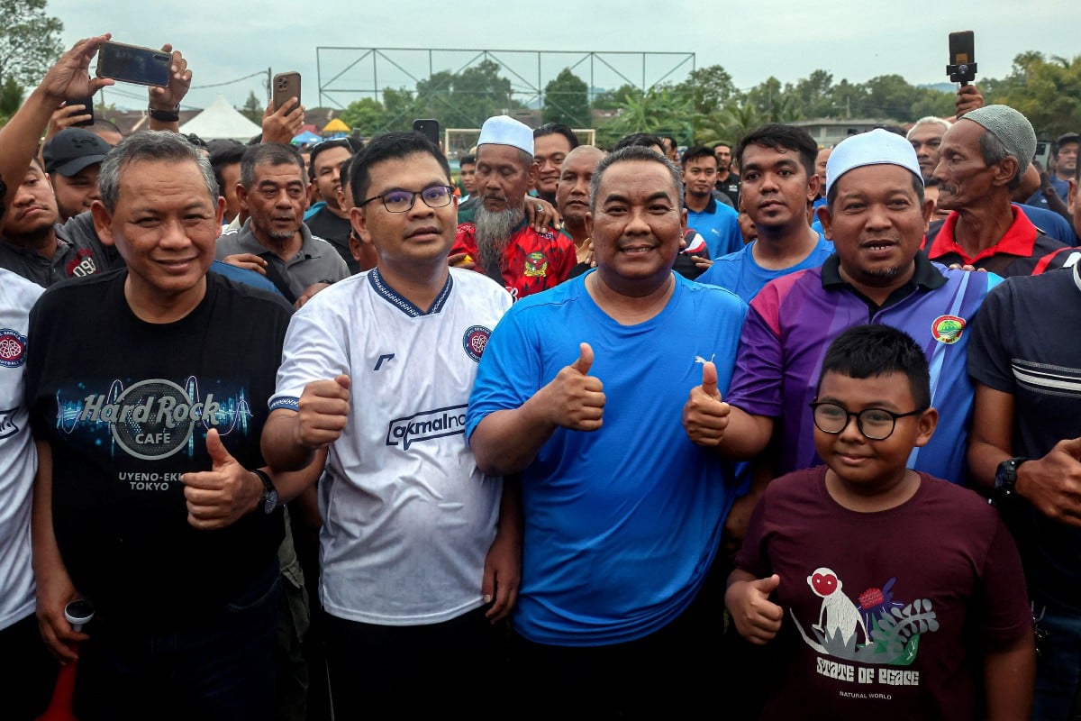 MUHAMMAD Sanusi bergambar bersama Akmal Nasrullah (dua, kiri) pada perlawanan bola persahabatan di Taman Pekatra Simpang Ampat. FOTO Bernama