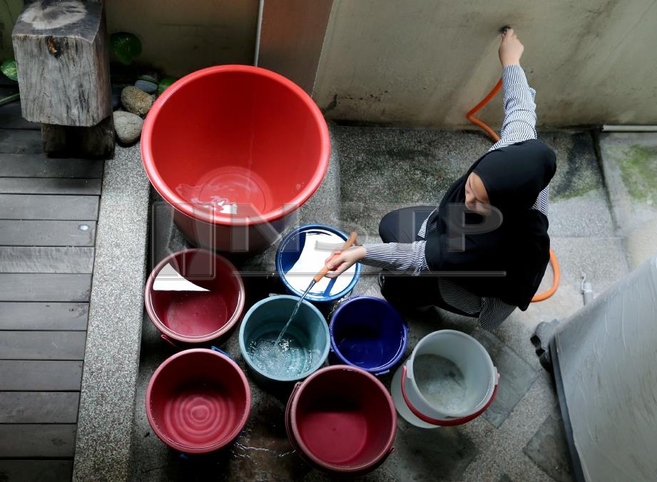 NURSYAHIRUNNISAA’ Abd Rahim, 20, mengisi air ke dalam bekas air bagi menghadapi gangguan bekalan air esok di beberapa kawasan di Petaling, Hulu Langat, Kuala Langat dan Sepang. FOTO Abd Rahim Rahmat.