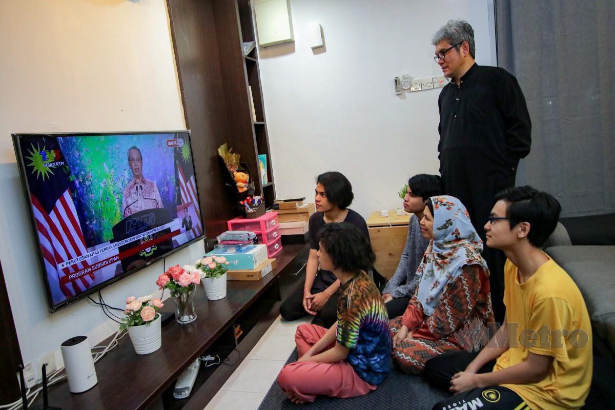 AHLI keluarga Raja Shahrul Azian Raja Mohd Din menonton perutusan khas Perdana Menteri sempena Tahun Baru 2021 ketika tinjauan di Bandar Seri Putra, Kajang. FOTO Aizuddin Saad
