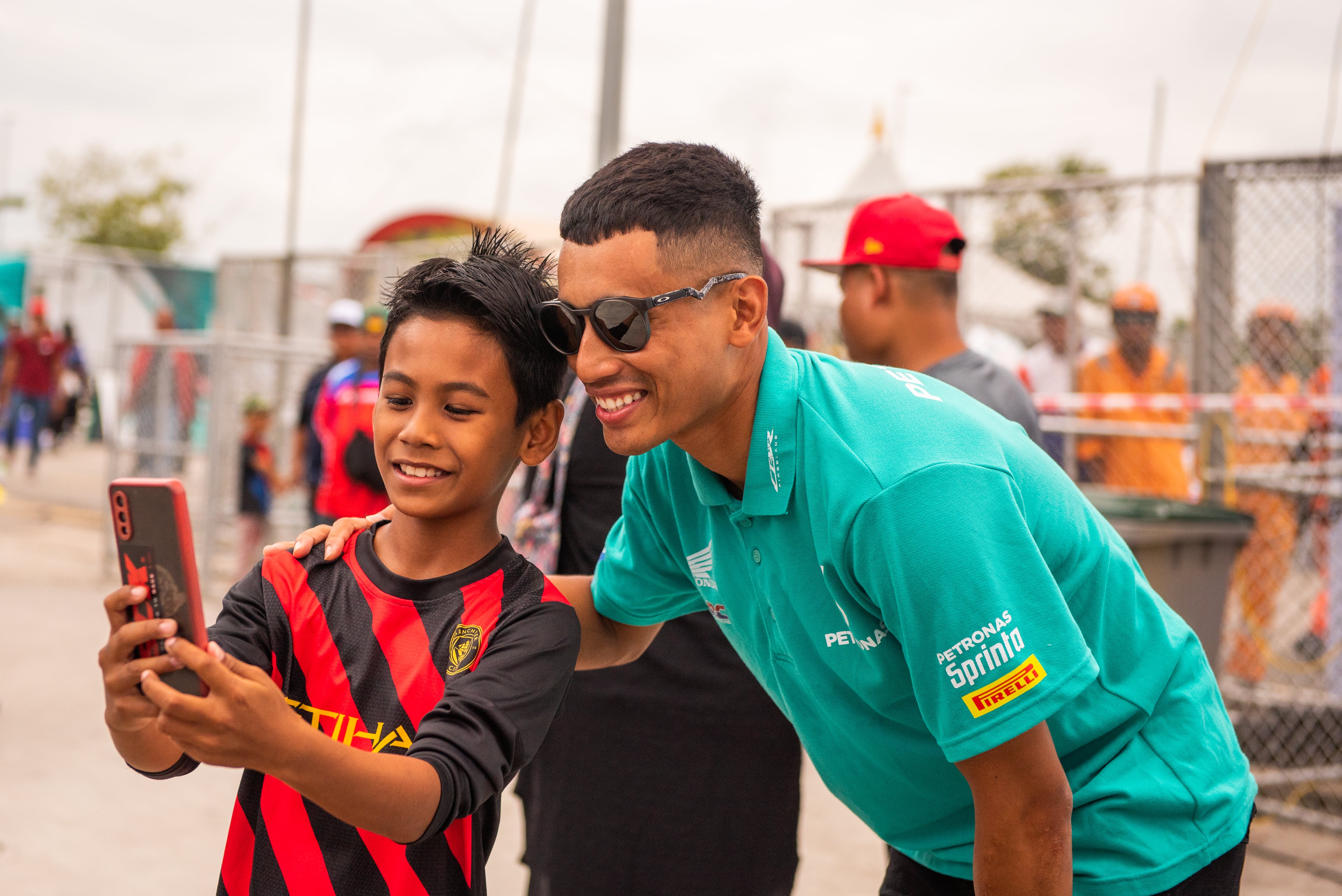 Pengunjung cilik bergambar kenangan bersama pelumba, Hafizh Syahrin Abdullah ketika Kejuaraan Petronas Malaysia Cub Prix di Jempol, Negeri Sembilan, baru-baru ini. - FOTO PETRONAS MOTORSPORTS.