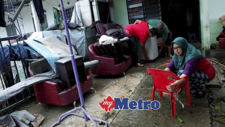 PENDUDUK Taman Mangga, Bukit Mertajam, Nurul Syazana Roshidi, 23, bersama ahli keluarga yang lain membersihkan barangan perabot dan keperluan yang terjejas dalam banjir sejak tiga hari lalu. FOTO Amir Irsyad Omar